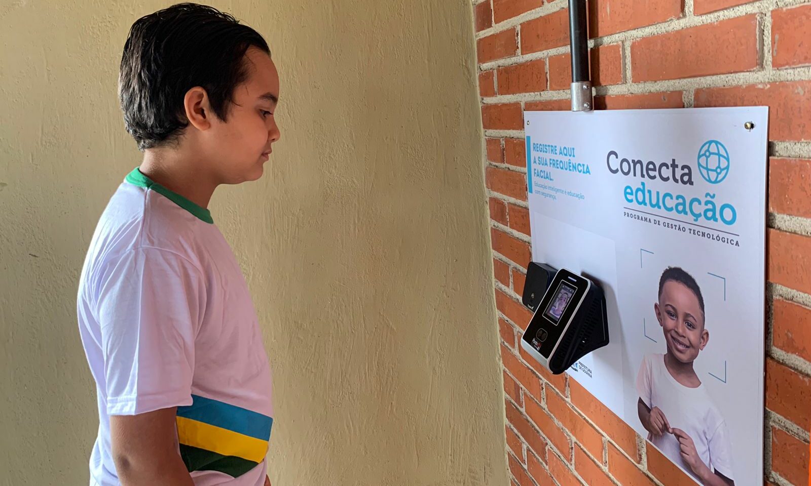 Imagem mostra uma criança em frente ao leitor facial. (Foto: Divulgação/Educação)