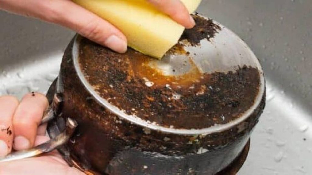 Pessoa lavando uma panela queimada