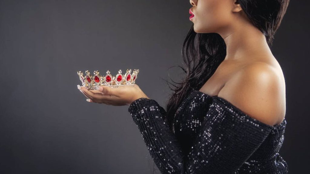 Mulher segurando uma coroa, sinal de que ela é uma pessoa exigente