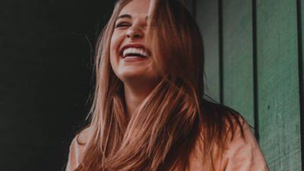 Mulher sorrindo, o bom humor pode te tornar mais atraente