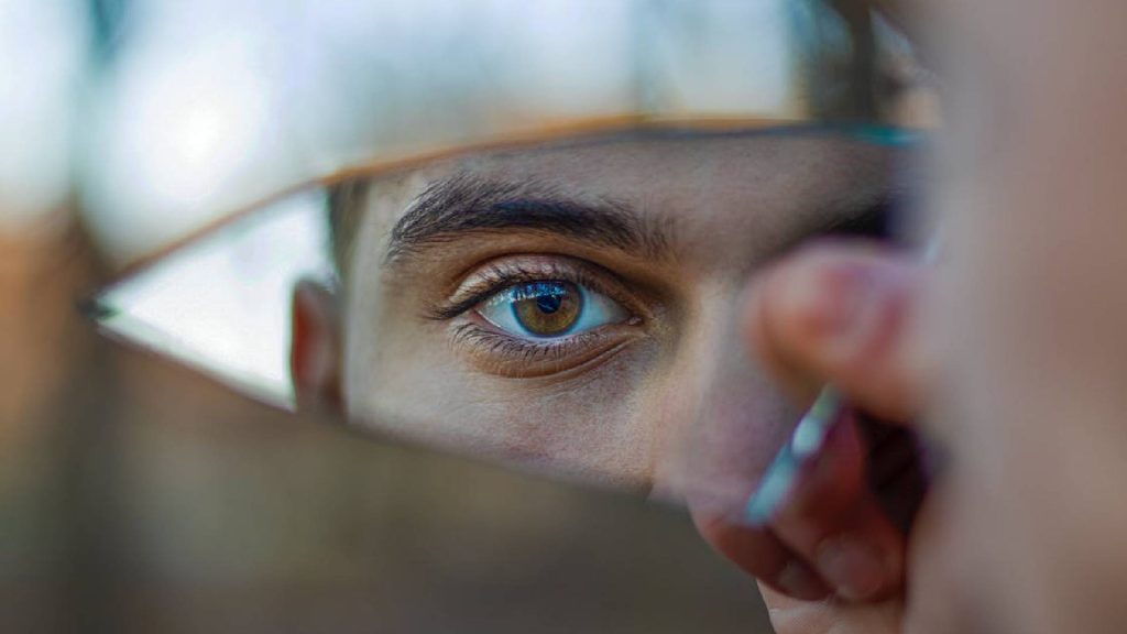 Homem olhando para um espelho quebrado simbolizando uma pessoa mentirosa