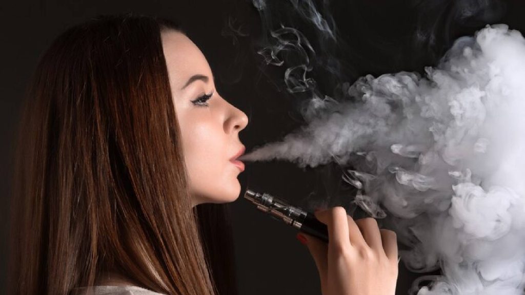 Mulher fumando cigarro eletrônico simbolizando os malefícios que o vaper traz