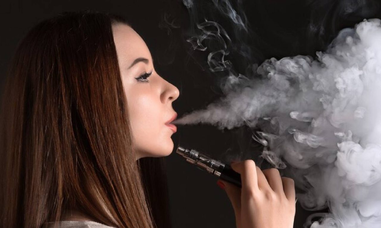 Mulher fumando cigarro eletrônico simbolizando os malefícios que o vaper traz