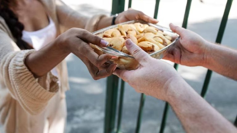 Mulher entregando biscoitos, um gesto de gentiliza de pessoas que tem o coração bom