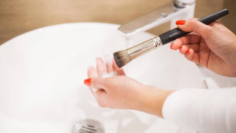 Mulher lavando pinceis de maquiagem simbolizando utilidades da pia do banheiro