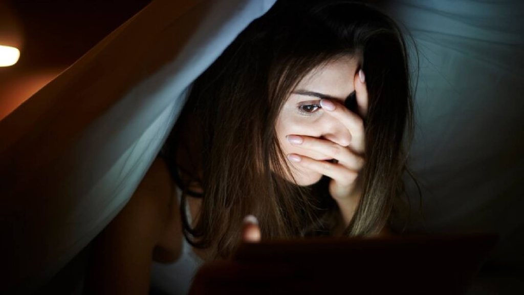 Mulher olhando para o celular simbolizando aquilo que uma pessoa malvada tenta esconder