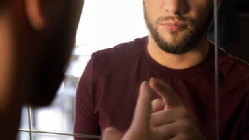 Rapaz se olhando no espelho simbolizando os homens infiéis