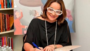 Gyovana Carneiro assina livro O Piano Encantado de Cristofori em evento de lançamento. (Foto: Arquivo Pessoal/Jornal UFG)