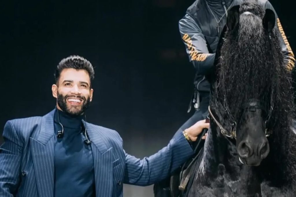 Imagem mostra Gusttavo Lima ao lado de cavalo.