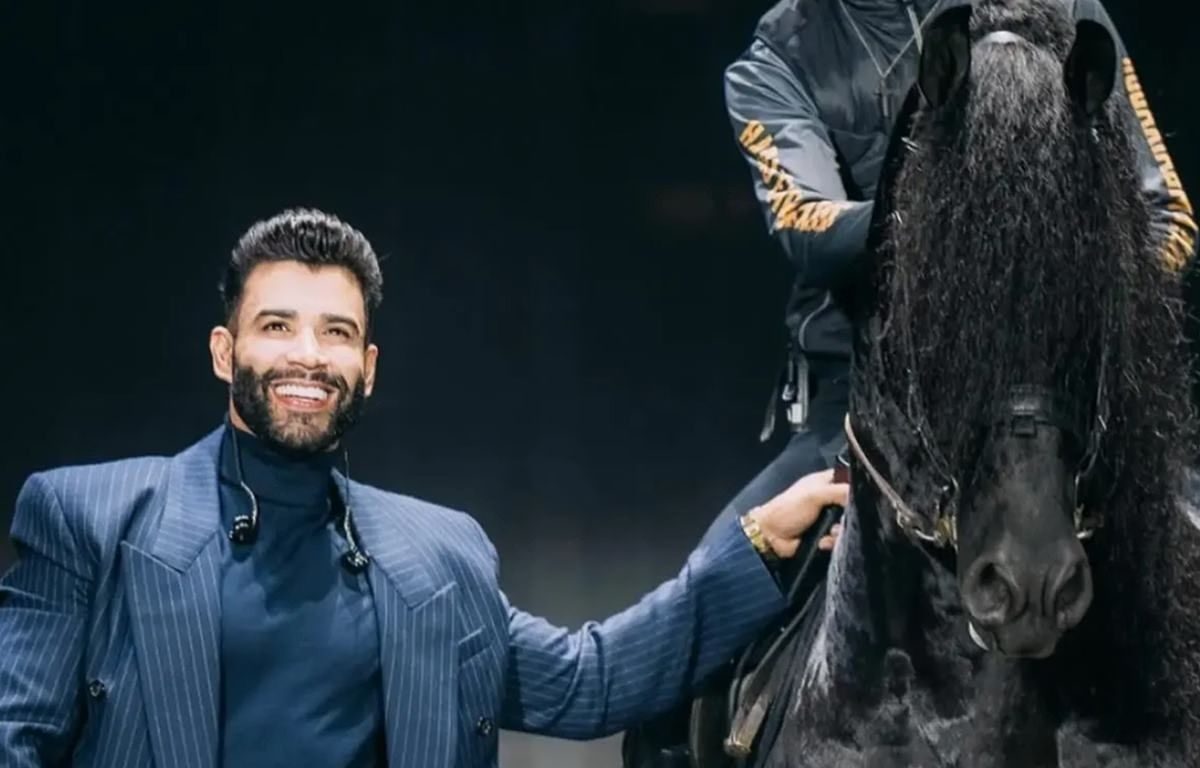 Imagem mostra Gusttavo Lima ao lado de cavalo.