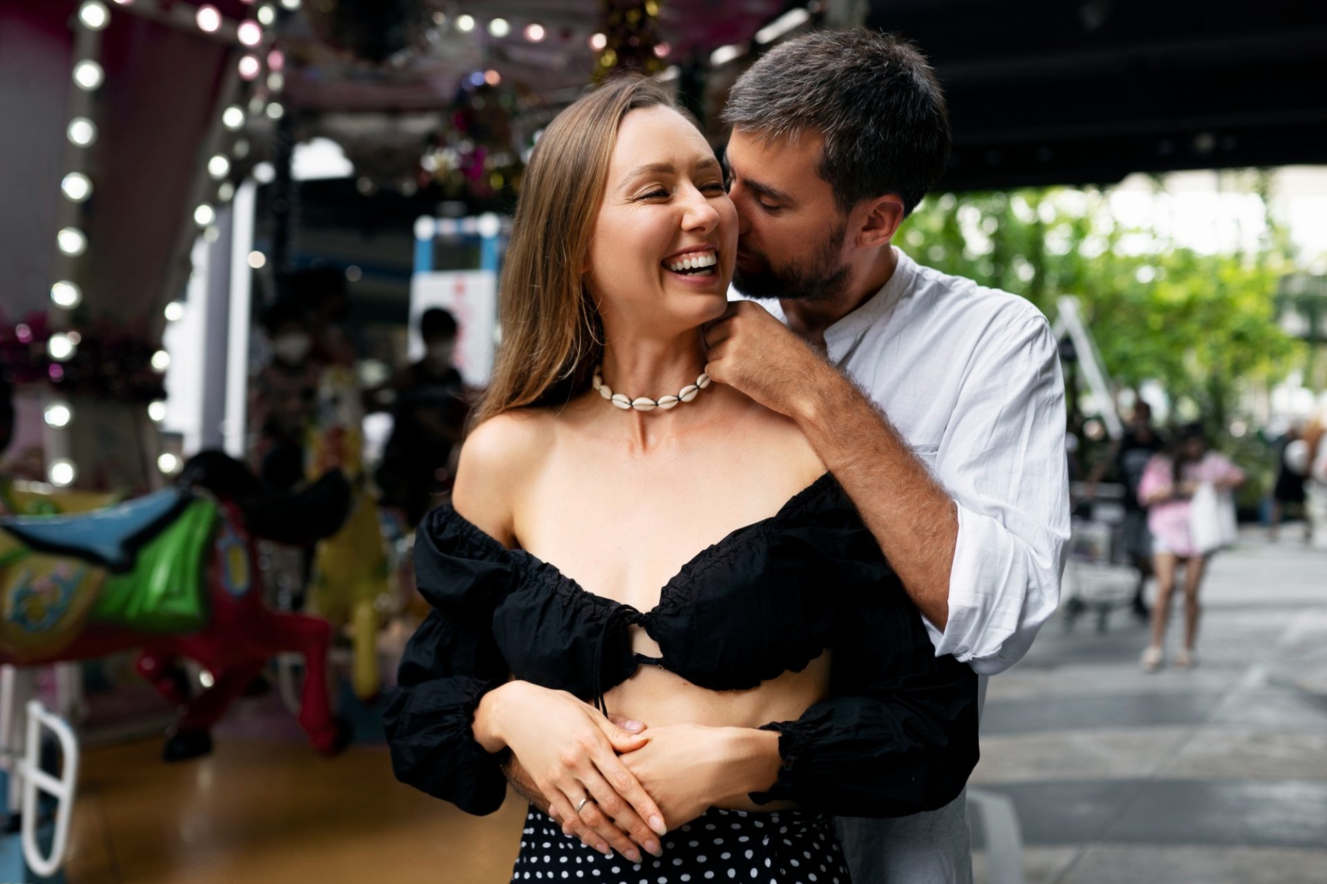Homem fala no ouvido de uma mulher que sorri ao receber elogio