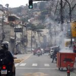 Durante operação policial contra o Comando Vermelho, bandidos ordenam fechamento de comércio e usam lixeiras incendiadas para bloquear a via no Rio de Janeiro.