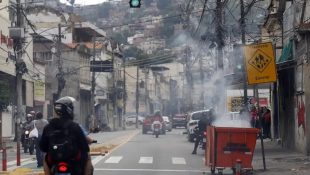 Durante operação policial contra o Comando Vermelho, bandidos ordenam fechamento de comércio e usam lixeiras incendiadas para bloquear a via no Rio de Janeiro.