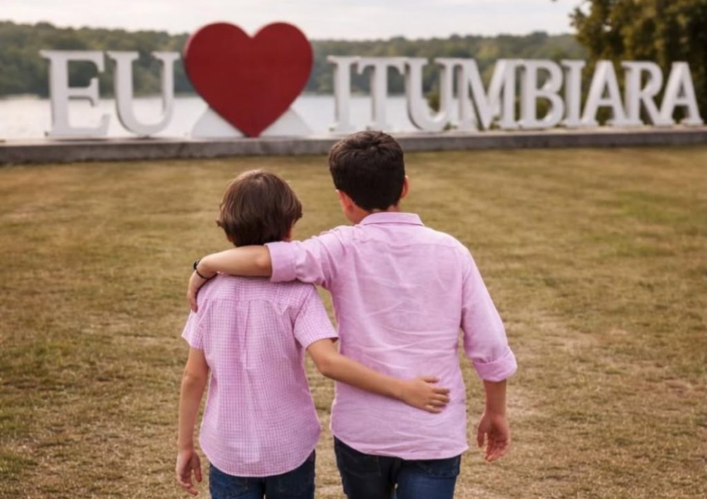 Netos do prefeito de Itumbiara, Dione Araújo, caminham abraçados rumo a monumento da cidade