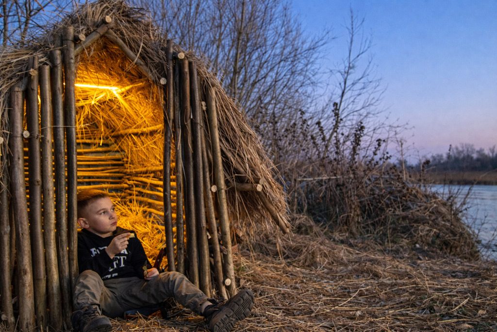 Menino de 12 anos constrói cabana à beira de rio com galhos e madeira e impressiona pela técnica de encaixe simples e funcional.