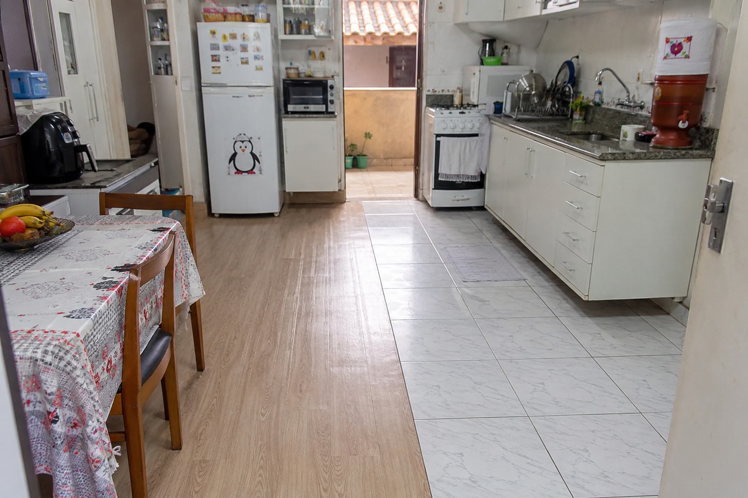 Cozinha pequena com piso vinílico novo aplicado sobre revestimento antigo, representando reforma rápida sem quebradeira