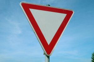 Placa de trânsito triangular com borda vermelha e centro branco: o que significa