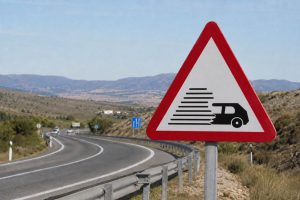 O que significa a placa de trânsito triangular branca com borda vermelha e o desenho de um carro com listras pretas, segundo o Detran