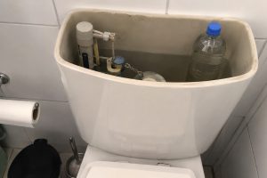 Garrafa PET cheia de água dentro da caixa acoplada do vaso sanitário