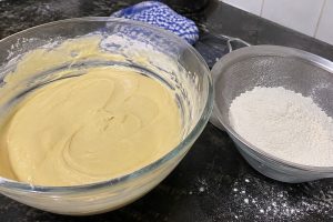 Massa de bolo homogênea ao lado de peneira com farinha de trigo
