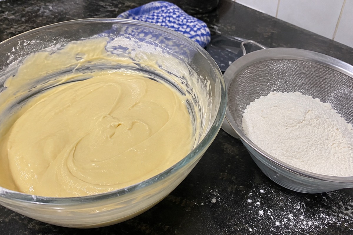 Massa de bolo homogênea ao lado de peneira com farinha de trigo
