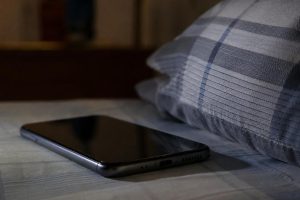 celular na cama ao lado do travesseiro
