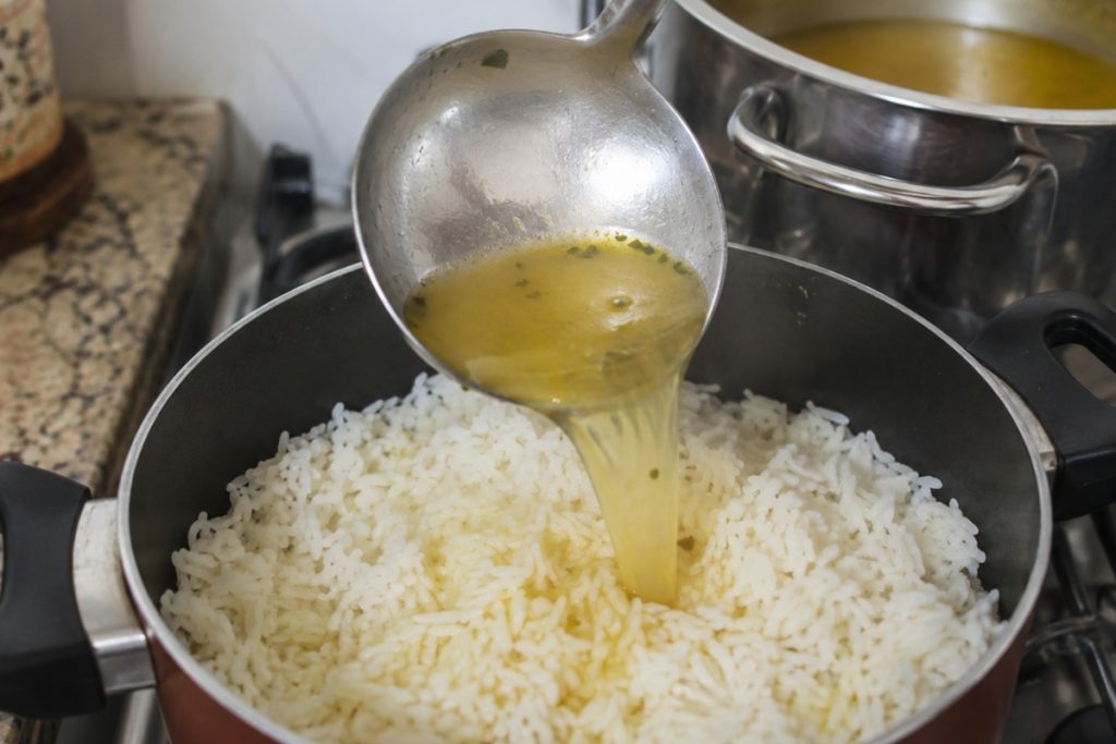 Caldo de legumes sendo adicionado no arroz