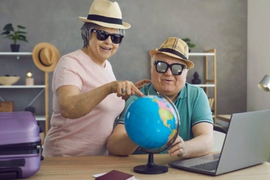 Um casal de aposentados planeja com alegria uma viagem pelo mundo, refletindo o cenário do artigo sobre como financiar uma primeira década de aposentadoria repleta de viagens
