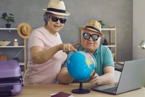 Um casal de aposentados planeja com alegria uma viagem pelo mundo, refletindo o cenário do artigo sobre como financiar uma primeira década de aposentadoria repleta de viagens