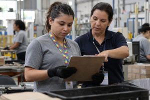 Funcionária recebe orientação durante treinamento em ambiente de produção industrial