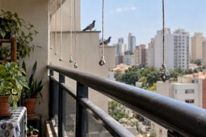 Parafusos presos a fios pendurados próximos ao guarda-corpo de uma varanda