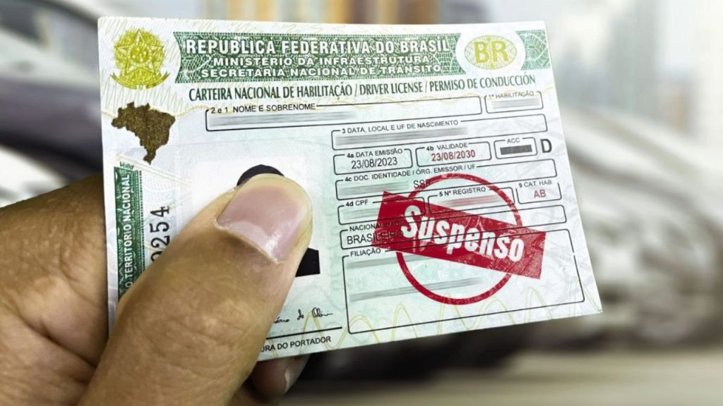 pessoa segurando CNH suspensa